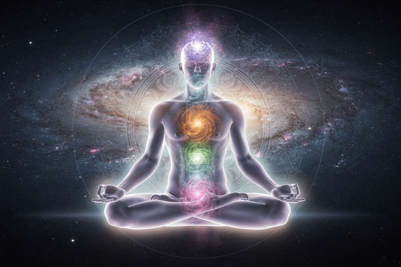 Frau sitzt in Lotusposition mit geschlossenen Augen während einer Meditationssitzung zur Aktivierung der Energiezentren.