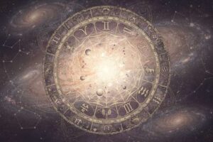 Frau sitzt nachdenklich am Fenster und schaut hinaus, während astrologische Symbole und Sternzeichen um sie herum schweben.
