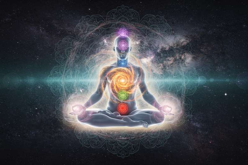 Frau in entspannter Yin-Yoga-Position mit visualisierten Energieflüssen durch die sieben Chakren des Körpers.