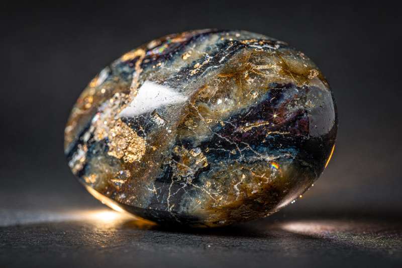 Raue Pietersite-Kristalle mit braunen und blauen Farbverl auf dunklem Hintergrund, symbolisiert Transformation und innere Kraft.