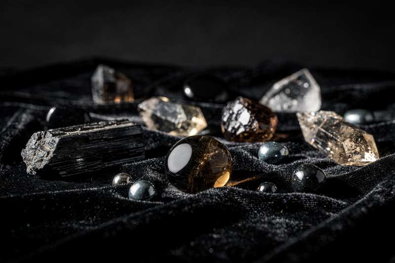 Verschiedene glänzende Schutzsteine und Kristalle in natürlichen Farbtönen, arrangiert zur Energiereinigung und zum Schutz der...